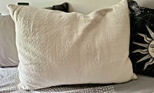 cream-colored pillow on a bed with other pillows
