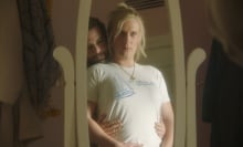 A woman looks at herself in the mirror, held by her partner, in a still from "Maddie's Secret."