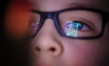 Instagram logo is reflected in boy's glasses. 
