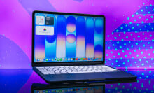 indigo macbook neo opened to home screen in front of purple background