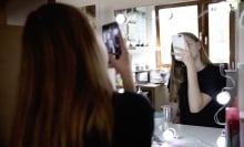 Teen girl takes selfie in front of a bathroom mirror.