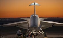 A technician inspecting the X-59 plane near its landing gear as the engine runs