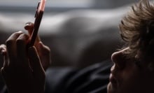 Teen boy looks at a phone. 
