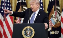 Trump stands at a White House podium pointing to the right. 