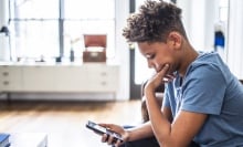 A teenager peers at his smartphone.