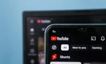 A laptop screen and a phone screen on the YouTube homepage.