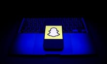 Snapchat logo on a smartphone, which is placed on an open laptop.