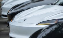 A row of Tesla vehicles in a parking lot.
