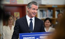 Gavin Newsom stands at a podium in the middle of a library.