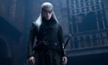 A man in armour wearing an eye patch stands in a dark room.