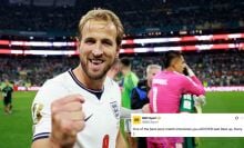 A football player raises his fist to the camera while grinning in celebration.