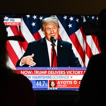 A couple watch President Donald Trump's victory speech from a TV screen.
