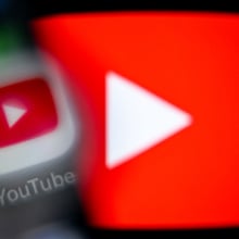 A blurry YouTube app icon over a large glowing YouTube play logo.