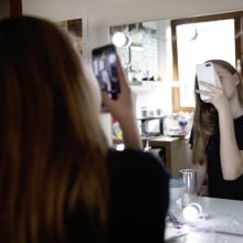 Teen girl takes selfie in front of a bathroom mirror.
