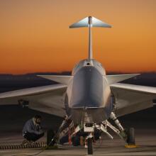 A technician inspecting the X-59 plane near its landing gear as the engine runs