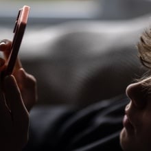 Teen boy looks at a phone. 