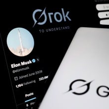 he Grok logo appears on a smartphone screen in front of Elon Musk X profile
