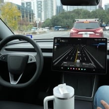 A safety monitor rides in the front passenger seat as a Tesla Robotaxi drives on South First Street in Austin on Wednesday, Jan. 21, 2026. 