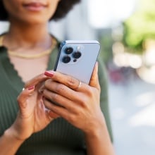 Woman holds cell phone in hand while she looks at it.