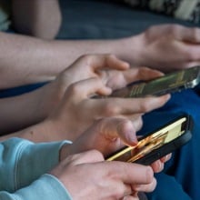 Three teenage boys look at their smartphone screens