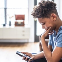 A teenager peers at his smartphone.