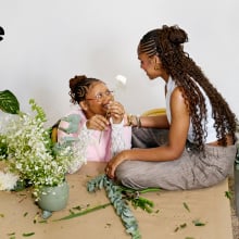 two black woman looking at each other, surrounded by plants