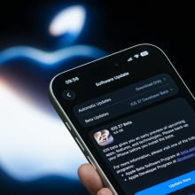 n iPhone displays the Apple iOS 27 Beta software update page in front of an illuminated Apple logo
