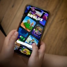 Child plays Roblox on a smartphone. 