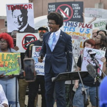 A group of protestors holding anti-xAI signs surround representative Justin Pearson. 