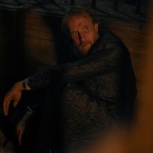 A man sits in a dark jail cell.