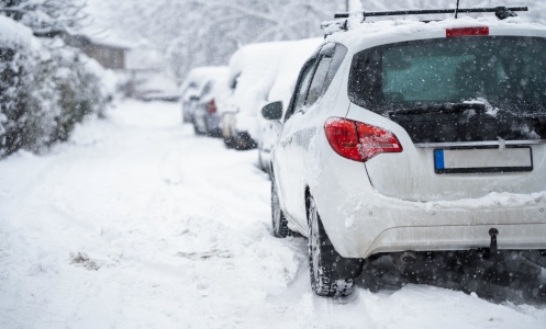 A bunch of parked cars covered in snow
