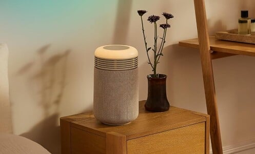 the Blueair mini restful air purifier sits in a bedside table in dim lighting.