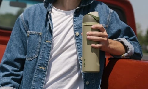 person standing outside holding green owala water bottle 