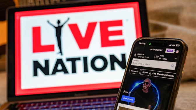 An iPhone displays the Ticketmaster app in front of a laptop showing the Live Nation logo. 