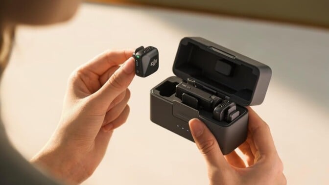 someone holds the DJI Mic mini receiver in their hand with one transceiver out of the case as we look over the person's shoulder