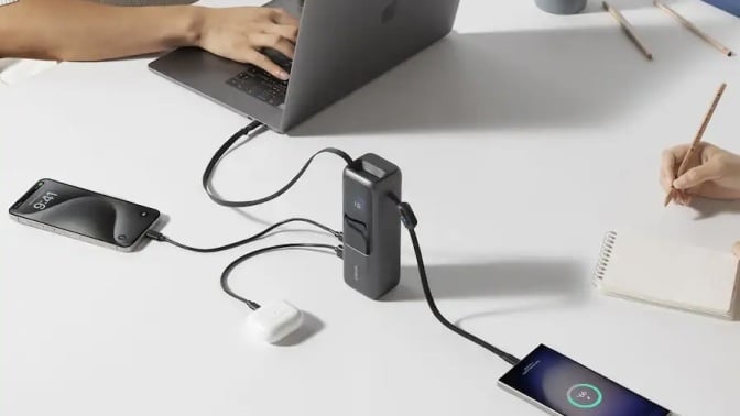 anker laptop charger on table with several devices plugged into it