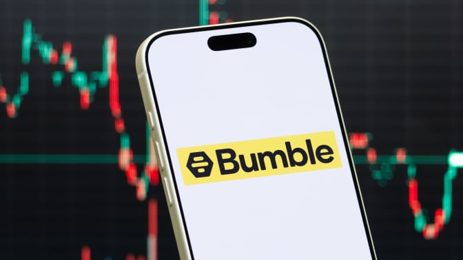 bumble logo on smartphone in front of stock market chart