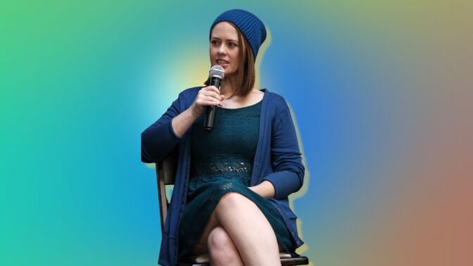 Jessica Mccabe speaking into a microphone on a gradient background
