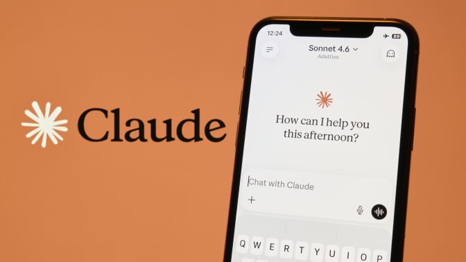 An iPhone against an orange backdrop displays the active interface of the Claude AI application, developed by Anthropic
