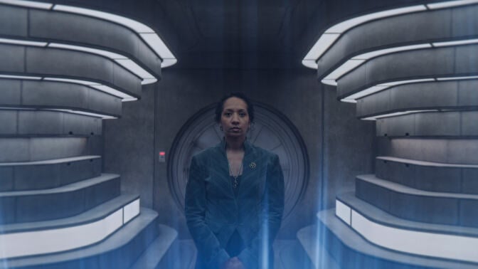A woman stands in a futuristic-looking room.