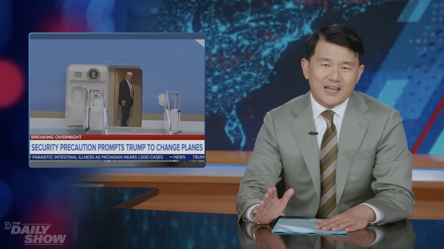 Ronny Chieng presents "The Daily Show" beside an image of Air Force One.