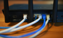 Ethernet cables are seen running from the back of a wireless router.