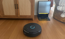 Narwal Flow 2 robot vacuum cleaning hardwood floor in front of self-empty dock and credenza