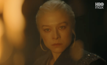 A woman is seen in a dark room, surrounded by flames.