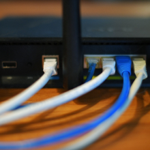 Ethernet cables are seen running from the back of a wireless router.