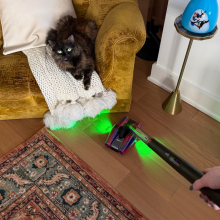Leah vacuuming floor with Dyson PencilVac near yellow chair and cat