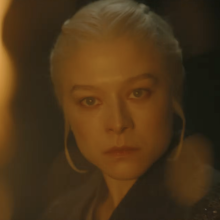 A woman is seen in a dark room, surrounded by flames.