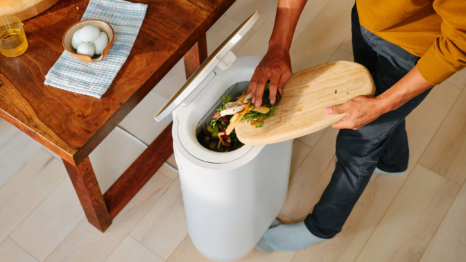 Person scraping food scraps from plate into Mill kitchen bin