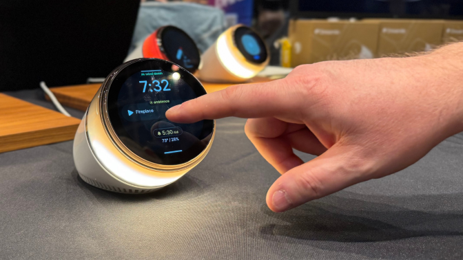 a man's hand tapping the screen of an ambient dreamie smart sunrise alarm clock