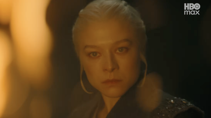 A woman is seen in a dark room, surrounded by flames.